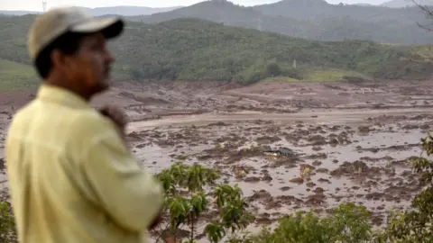 Getty Images A man looks at where a dam burst in the village of Bento Rodrigues, in Mariana, the southeastern Brazilian state of Minas Gerais on November 6, 2015.