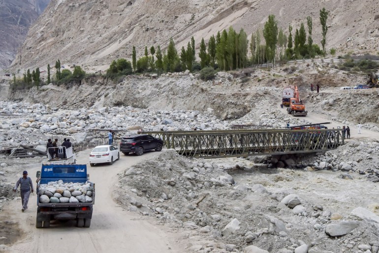 In this picture taken on June 9, 2022, locals and tourists drive through a temporary bridge after the main bridge was swept away by a lake outburst because of a melting glacier, in Hassanabad village of Pakistan's Gilgit-Baltistan region. - Pakistan is home to more than 7,000 glaciers, more than anywhere else on Earth outside the poles. Rising global temperatures linked to climate change are causing the glaciers to rapidly melt, creating thousands of glacial lakes. (Photo by Abdul MAJEED / AFP) / To go with 'Pakistan-climate-flood', by Zain Zaman JANJUA