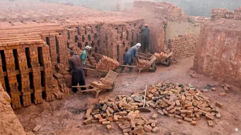 Getty Labourers work at a brick kiln engulfed in smog