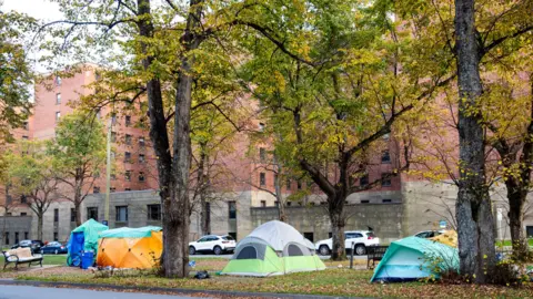 Kelly Clark/BBC An image showing four tents set up on a grassy median in downtown Halifax 