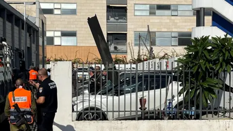 Reuters Part of a rocket sticks out from a parked car in the Israeli town of Raanana, near Tel Aviv, central Israel (6 November 2024)