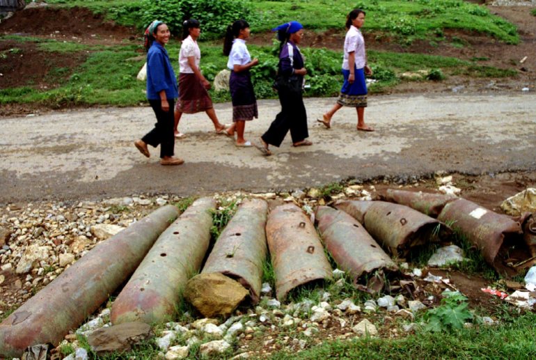 Laotian women walk past bombs and shells lie on the streets in this northern province. From 1964-1973, US planes dropped two million tonnes of bombs in Laos, many of them unexploded, still scattered throughout the countryside causing casualties to the Laotian people