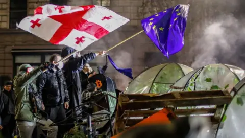 EPA 
Georgian opposition supporters wave EU and Georgian flags during a protest in front of Parliament building in Tbilisi, Georgia, early 30 November 2024