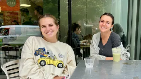 BBC Lola Nordlinger (left) and Keely Ganong (right) sit in a coffee shop