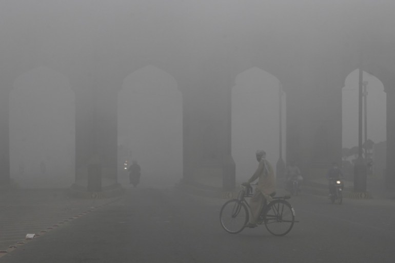 Commuters move along a road amid heavy smoggy conditions in Lahore