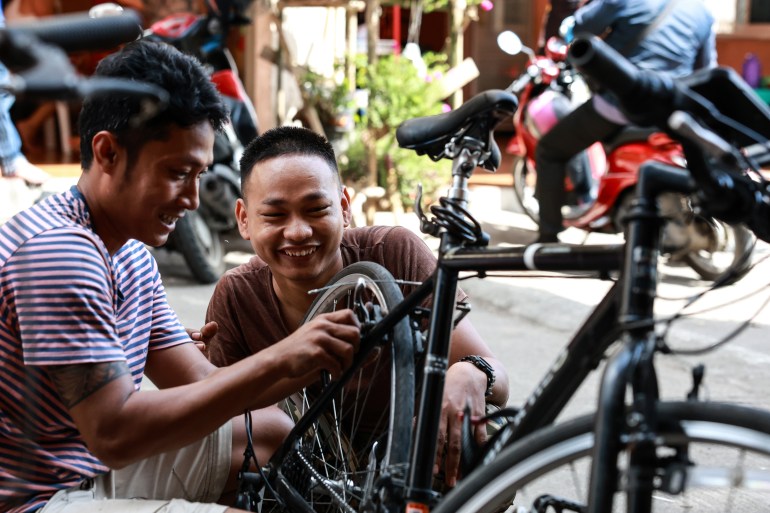 A repair instructor, former Myanmar navy personnel, left, and a regime defector, fix a bicycle during an e-bike and bicycle repair workshop near the Thailand-Myanmar border on November 1, 2024 [Valeria Mongelli/Al Jazeera]