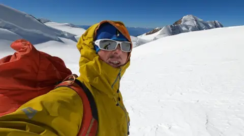 Ondrej Huserka / Facebook Ondrej Huserka dressed in yellow and wearing sunglasses, standing in snow-covered mountain landscape