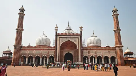 Getty Images This photograph taken on October 8, 2024 shows tourists visiting the Jama Masjid in the old quarters of Delhi. Residents of India's capital New Delhi choked in a blanketing toxic smog on November 18 as worsening air pollution surged past 60 times the World Health Organization's recommended daily maximum. (Photo by Sajjad HUSSAIN / AFP) (Photo by SAJJAD HUSSAIN/AFP via Getty Images)
