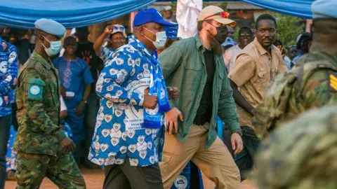 Getty Images President Faustin-Archange Touadéra arrives at a stadium with a white bodyguard ahead of the presidential elections in Bangui, in December 2020.