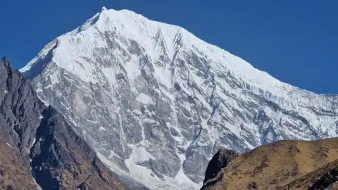 Judith Swift The mountain, which is completely covered in snow at the peak and then grey and white further down the slope