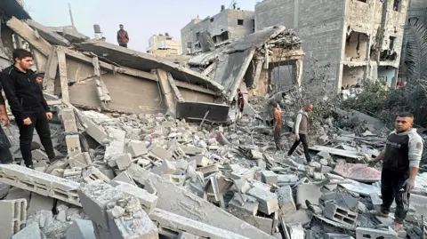 Reuters Palestinians gather at a pile of rubble at the site of an Israeli strike on a house, in Jabalia in the northern Gaza Strip