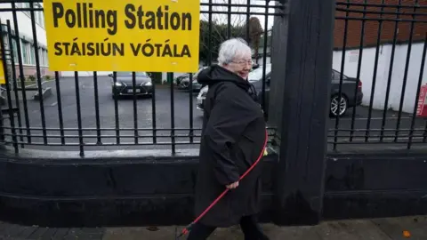 PA Media A woman walks with a dog lead outside of a polling station