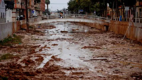 Reuters A person crosses the La Saleta ravine that recently overflowed due to heavy rainfall in Aldaia, Valencia