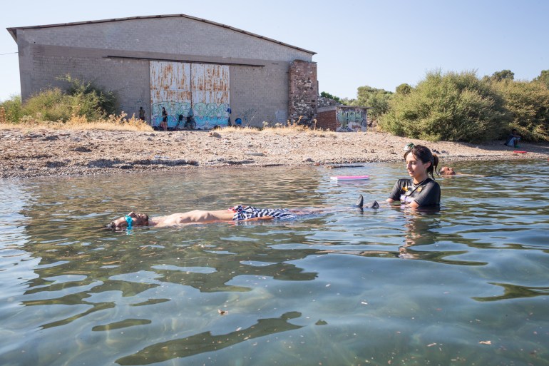 Mitali Desai teaches Hoissein* how to float by having him lie on his back in the water. [Giacomo Sini/Al Jazeera]