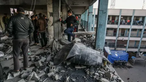 AFP Palestinians inspect damage following an Israeli air strike on a school housing displaced families in Khan Younis, southern Gaza (16 December 2024)