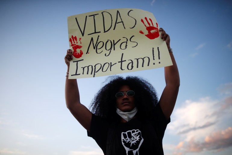 A woman holds up a sign that reads: Vidas negras importam.