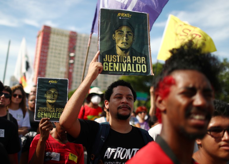 A protester holds up a picture with the words, "Justicia por Genivaldo"