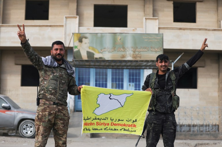 Members of the Kurdish-led Syrian Democratic Forces (SDF) a flag in Deir al-Zor, after U.S.-backed alliance led by Syrian Kurdish fighters captured Deir el-Zor, the government's main foothold in the vast desert, according to Syrian sources, in Syria December 7, 2024. REUTERS/Orhan Qereman