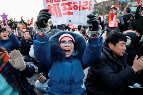 Reuters People in South Korea celebrate after parliament passes a motion to impeach President Yoon Suk Yeol