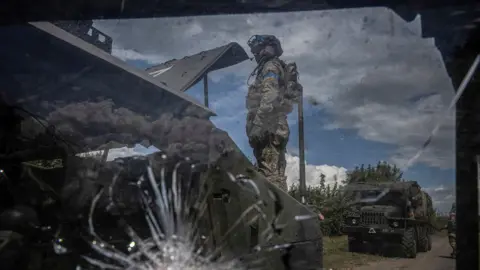 Reuters A Ukrainian soldier stands next to a broken military vehicle, in Sumy region, Ukraine August 11, 2024