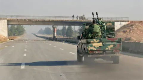 Getty Images Rebel forces drive down a highway in Syria