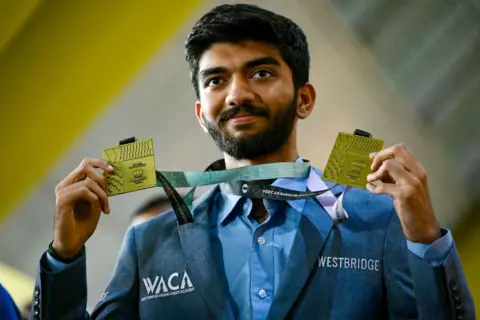 Getty Images Gold medalist grandmaster Dommaraju Gukesh, shows his medals upon his arrival at the Chennai International Airport in Chennai on September 24, 2024, after his win at the 45th FIDE Chess Olympiad Budapest 2024. (