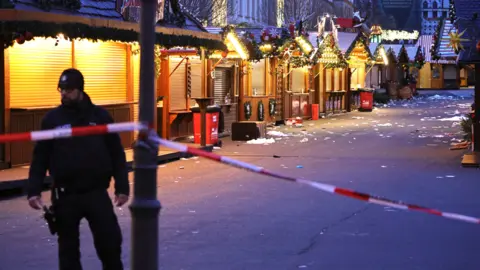 Getty Images A policeman walks through the shuttered Christmas market the day after a terror attack that has left five people dead, including a small child, and over 200 injured on December 21, 2024 in Magdeburg,