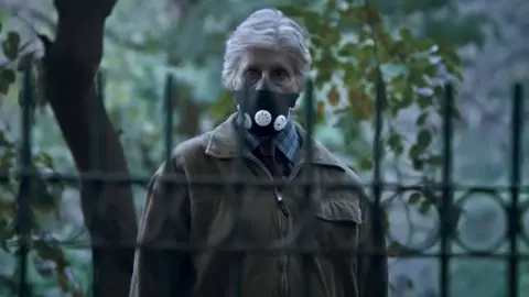 Screengrab from Pink's trailer Amitabh Bachchan seen wearing a mask as he stands in a park behind metal grills