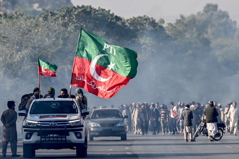 Supporters of jailed former prime minister Imran Khan's Pakistan Tehreek-e-Insaf (PTI) party march towards Islamabad after clearing shipping containers placed by authorities during a demonstration demanding Khan's release, in Hasan Abdal in Punjab province on November 25, 2024. - Pakistan's capital was under total lockdown on November 24, with mobile internet cut and thousands of police flooding the streets as supporters of jailed ex-prime minister marched on the city. (Photo by Aamir QURESHI / AFP)