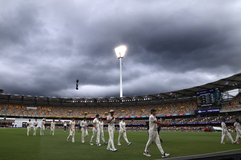 Australias captain Pat Cummins (C) leads his team off the ground due to a rain delay on day five of the third cricket Test match between Australia and India at The Gabba in Brisbane on December 18, 2024. (Photo by DAVID GRAY / AFP) / -- IMAGE RESTRICTED TO EDITORIAL USE - STRICTLY NO COMMERCIAL USE --