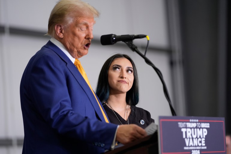 Donald Trump speaks at a podium while Alexis Nungaray looks on