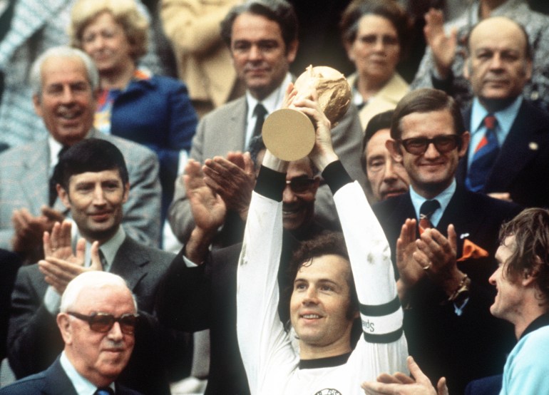 Franz Beckenbauer holding trophy.