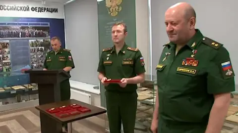 Russian defence ministry Igor Kirillov on the right and wearing a green Russian military uniform is seen handing out medals to other soldiers in the Russian army