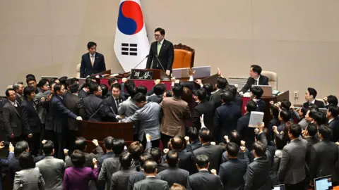 Getty Images Lawmakers protesting and crowding around parliament speaker Woo Won-shik