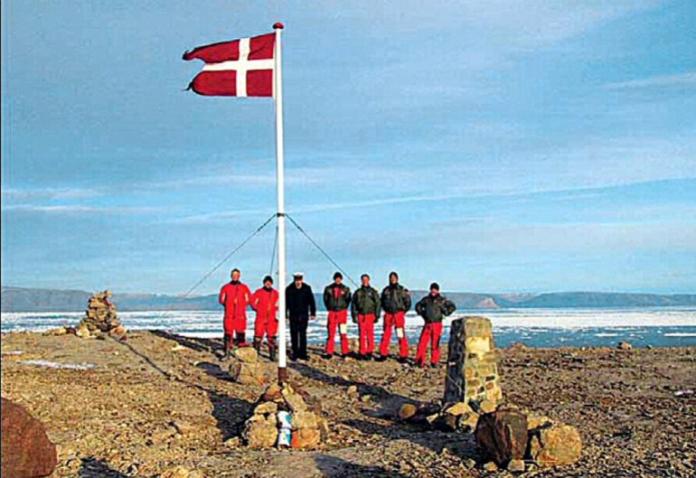 A group of Danish soldiers and the Danish flag stand on the Hans Island between Greenland and Canada