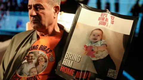 Reuters Eli Bibas, grandfather of the youngest hostage in Gaza, Kfir Bibas, holds a poster calling for his release