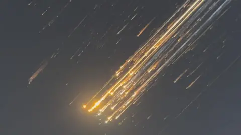 Reuters Orange balls of light fly across the sky from top right to bottom left as debris from a SpaceX rocket