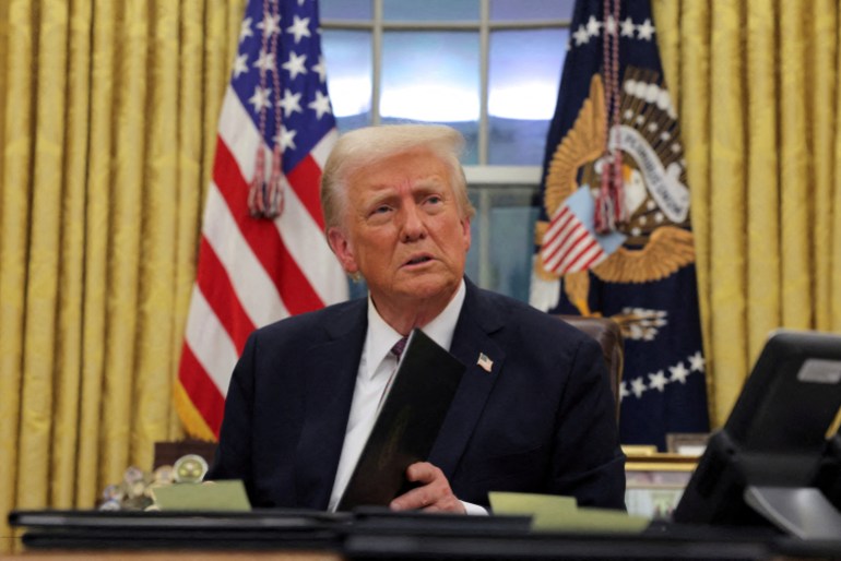 Donald Trump signs executive orders at his desk in the Oval Office