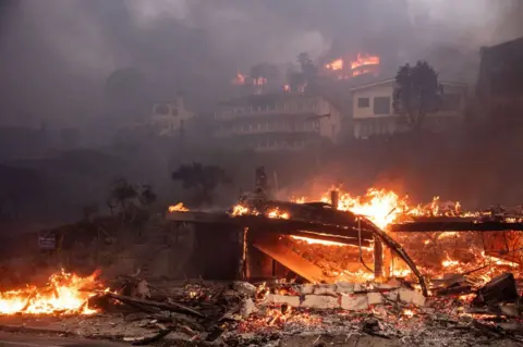 Getty Images A photo showing beachfront and hillside homes in Malibu, California, burning in the Palisades fire on Wednesday, January 8, 2025.