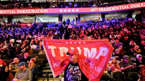 Getty Images A man holds up a red Trump flag at the president-elect's pre-inauguration rally in Washington. 