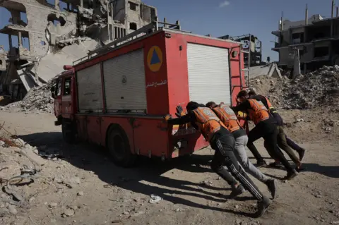 AFP Civil Defence rescuers push a fire truck amid destruction in the Shujaiyah neighbourhood in Gaza City in November.