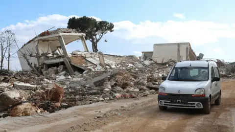 Reuters People drive past a damaged site in the southern Lebanese village of Khiam, near the border with Israel
