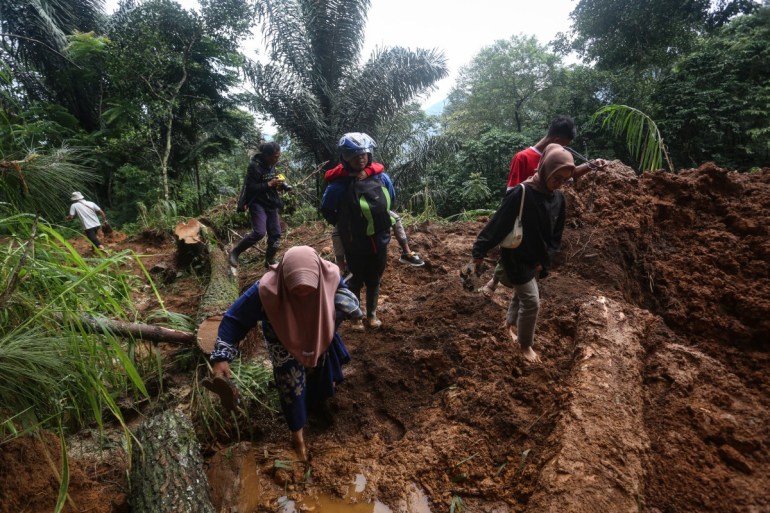 People walk through the site of a landslide triggered by heavy rain two days ago in Mudal village, near Pekalongan city in Central Java on January 22, 2025