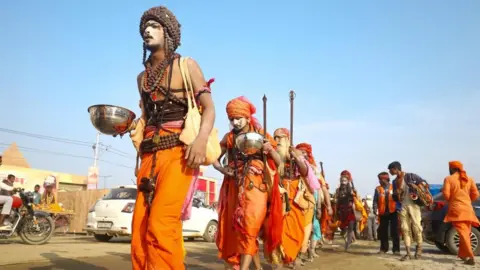 Ankit Srinivas A group of men in saffron clothing walking in the festival grounds