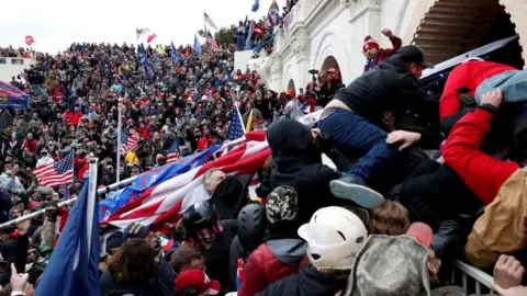 Reuters A crowd of Trump supporters surrounding the US Capitol building wave flags and pump fists