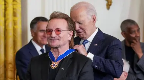 Getty Images US President Joe Biden presents the Presidential Medal of Freedom to Bono in the East Room of the White House on 4 January 2025